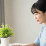 自宅の明るいデスクで、女性がノートパソコンを開き、新しいことを始める瞬間の、希望に満ちた横顔