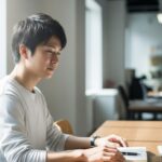 明るい自然光が差し込むオフィスで、デスクに向かう男性