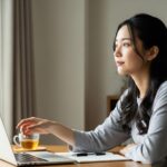 柔らかな自然光が差し込む静かな部屋で、デスクに向かう女性